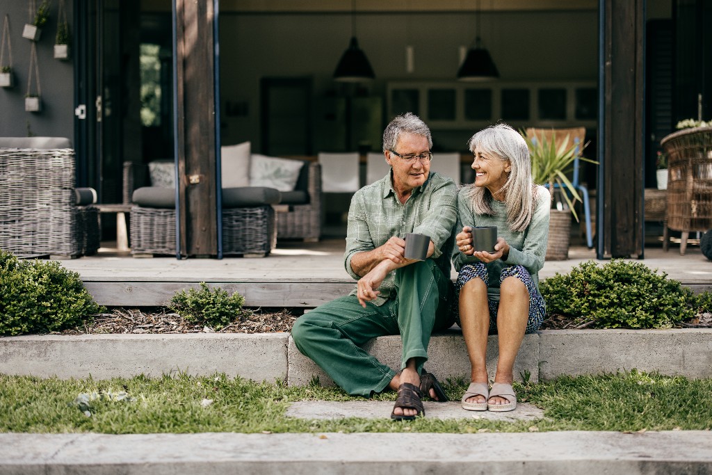 Retired couple enjoying coffee together outside their home