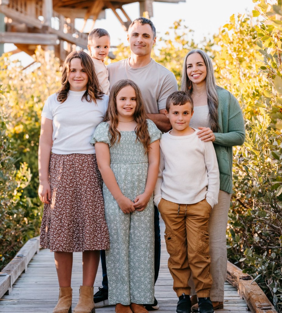 Tony Root with his wife and four children on a boardwalk at golden hour