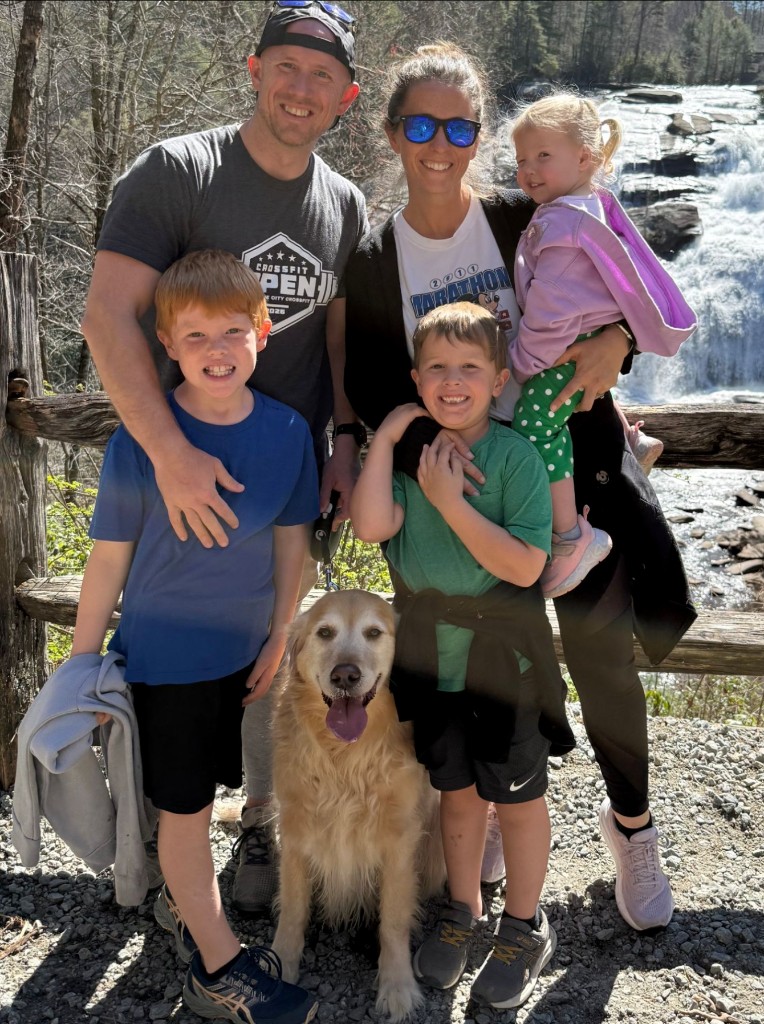 Trevor Shultz with his wife Emily, their three children, and their dog outdoors near a waterfall