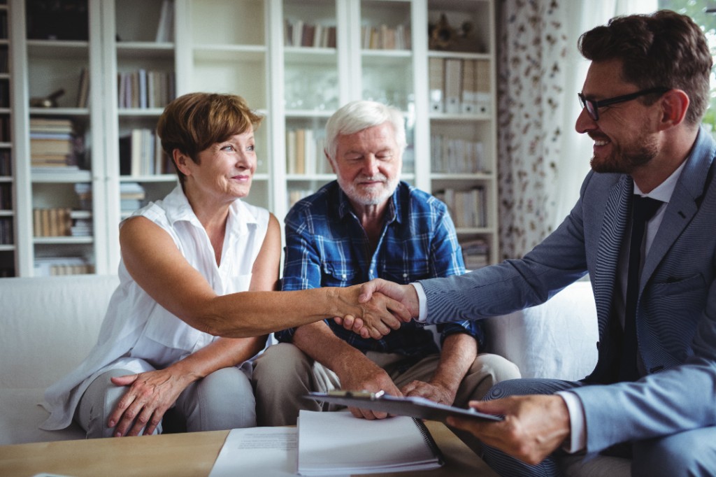 Financial advisor shaking hands with a smiling retired couple
